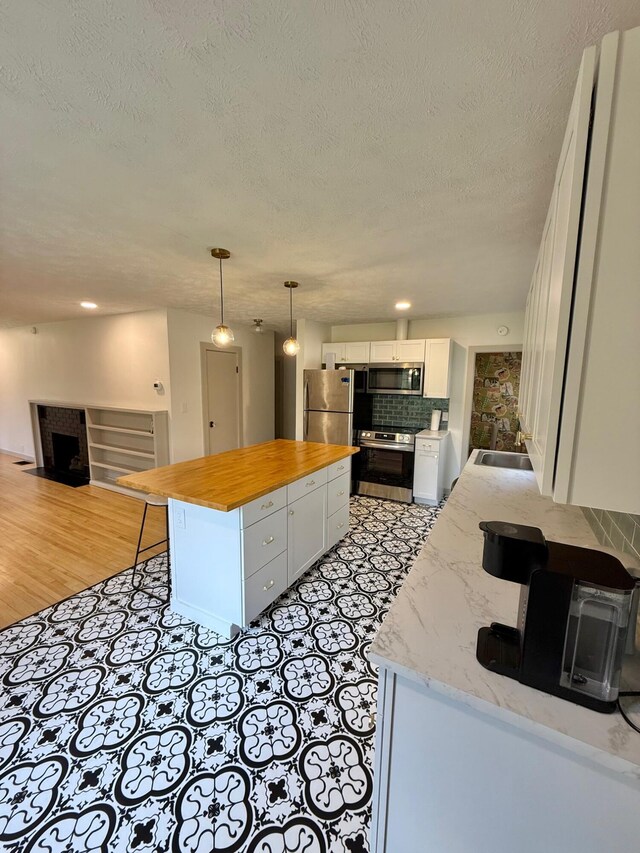5795 S M37 Hwy, Hastings, MI 49058 - kitchen with tasteful backsplash, wood counters, white cabinetry, a kitchen island, and appliances with stainless steel finishes
