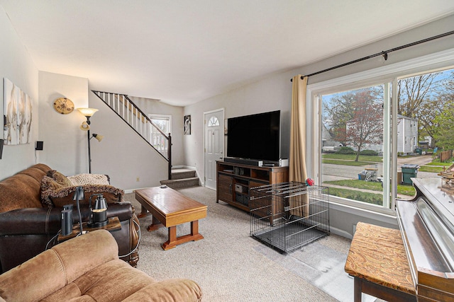 living area featuring carpet flooring, baseboards, and stairway