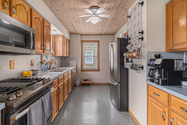 kitchen with appliances with stainless steel finishes, a sink, a ceiling fan, baseboards, and wooden ceiling