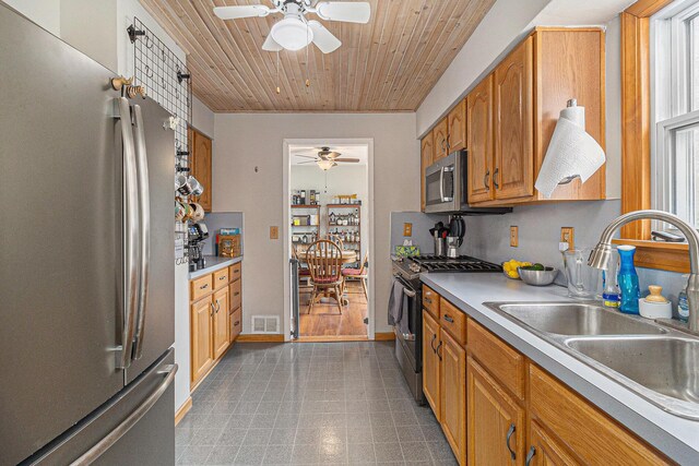 kitchen with appliances with stainless steel finishes, a ceiling fan, a sink, wood ceiling, and light countertops