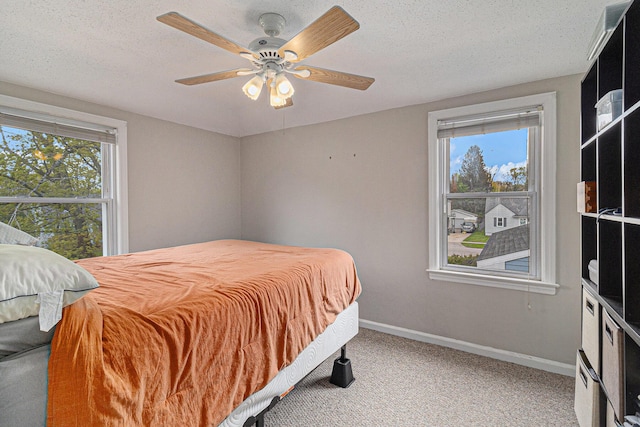 carpeted bedroom featuring baseboards, a textured ceiling, and a ceiling fan