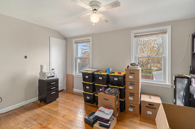 home office with light wood finished floors, ceiling fan, plenty of natural light, lofted ceiling, and baseboards