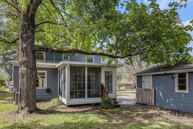 back of property featuring a sunroom and fence
