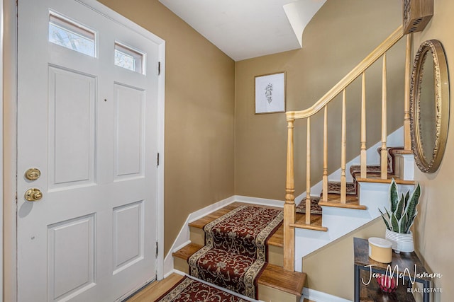 entryway featuring stairs, baseboards, and wood finished floors
