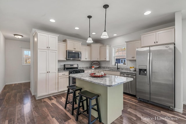 7177 Longview Ct, Delton, MI 49046 - kitchen with appliances with stainless steel finishes, a sink, a center island, light stone counters, and dark wood-type flooring