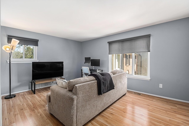 living room featuring visible vents, light wood-style flooring, and baseboards