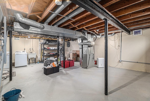 unfinished basement featuring separate washer and dryer, heating unit, and a sink