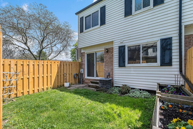 exterior space with central AC, brick siding, fence, and a lawn