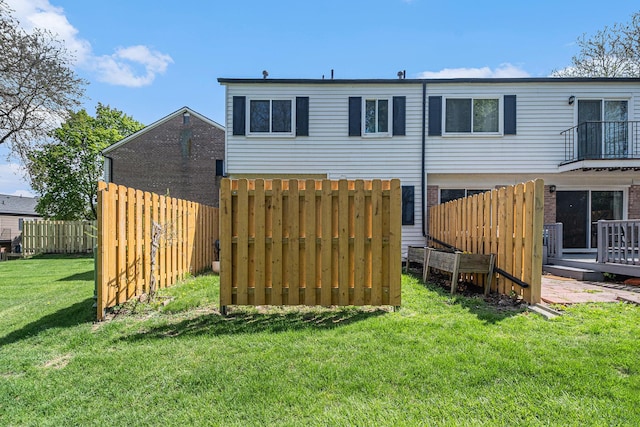 back of property with a yard, fence, and a deck