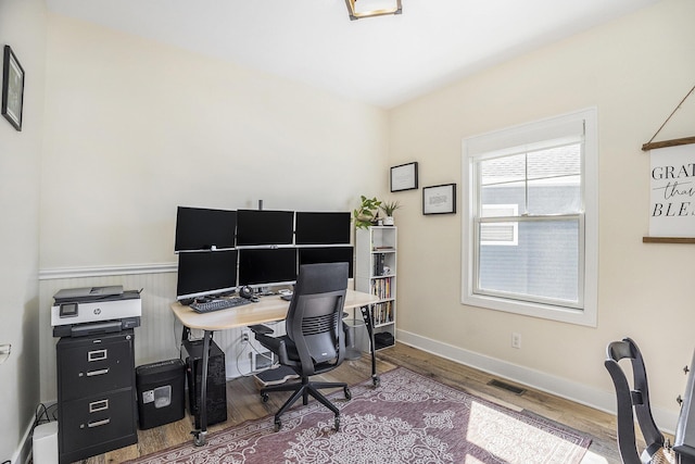 office area with baseboards, visible vents, and wood finished floors
