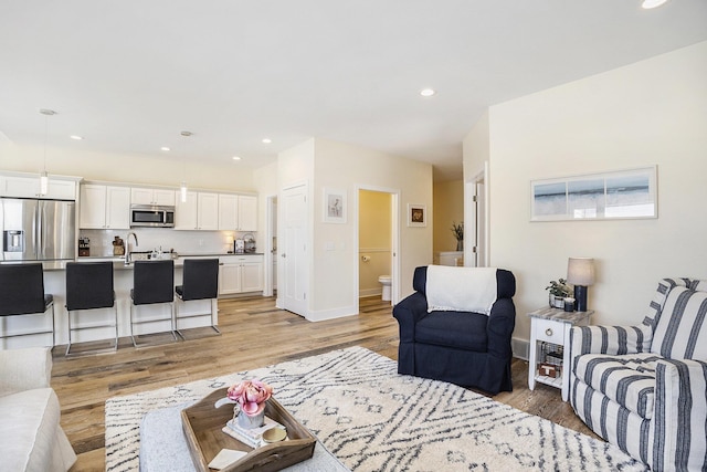 living room with baseboards, light wood-style floors, and recessed lighting