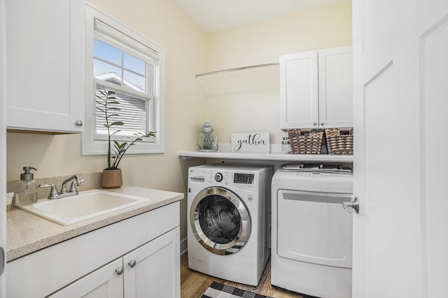 clothes washing area with cabinet space, independent washer and dryer, light wood-style flooring, and a sink