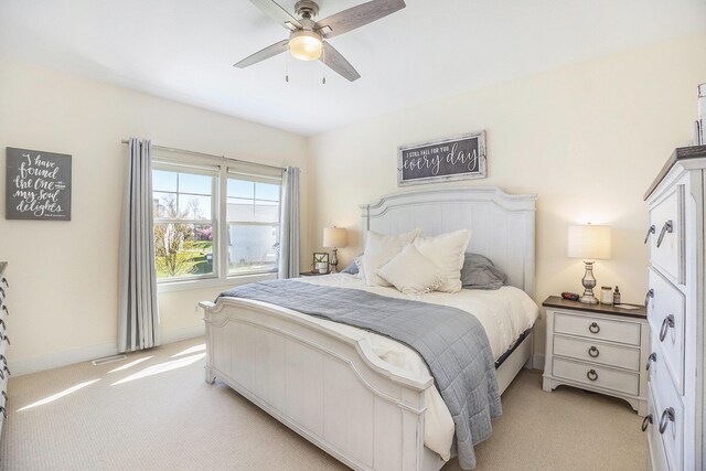 bedroom featuring light colored carpet, baseboards, and a ceiling fan