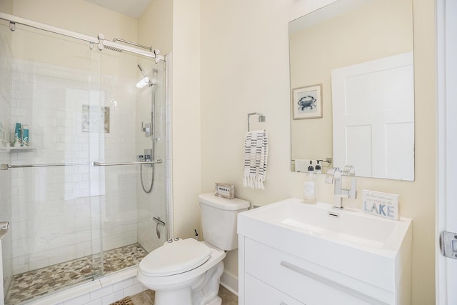 bathroom featuring toilet, vanity, and a stall shower