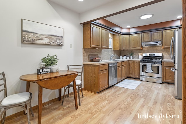 1013 Country Gdns NW, Walker, MI 49534 - kitchen with light wood-style flooring, brown cabinets, a sink, stainless steel appliances, and under cabinet range hood