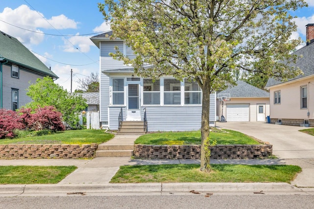 view of front of home featuring an outbuilding, a detached garage, a sunroom, concrete driveway, and a front lawn