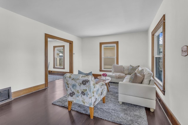 living room featuring baseboards, visible vents, and wood finished floors