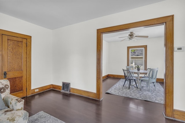 living area featuring wood finished floors, baseboards, and ceiling fan