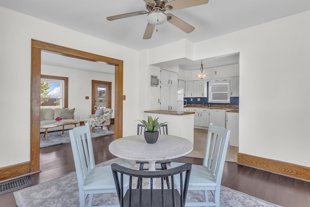 dining space with light wood-style flooring, a ceiling fan, and visible vents