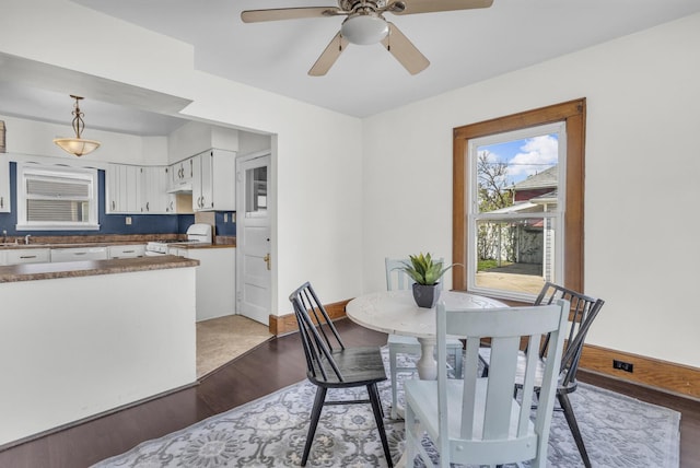 dining space featuring a ceiling fan, baseboards, and dark wood-type flooring