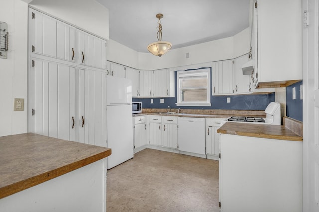 kitchen with exhaust hood, white appliances, hanging light fixtures, a sink, and white cabinets