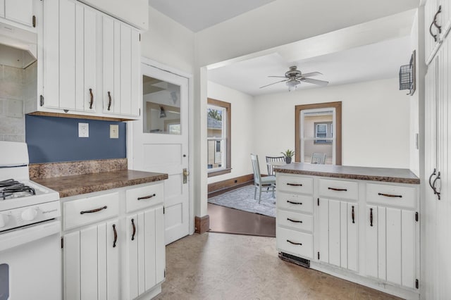 kitchen featuring under cabinet range hood, dark countertops, gas range gas stove, and a ceiling fan