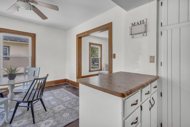 kitchen featuring a ceiling fan, dark countertops, white cabinets, dark wood-type flooring, and baseboards