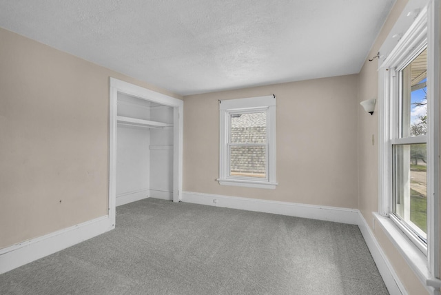 unfurnished bedroom with carpet, a textured ceiling, and baseboards