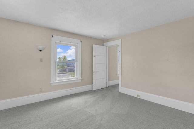 spare room featuring a textured ceiling, carpet flooring, and baseboards