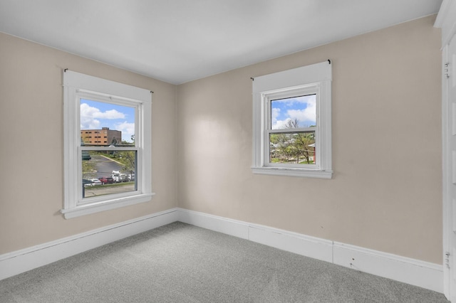carpeted empty room featuring a wealth of natural light and baseboards