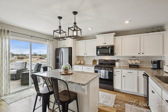 560 Pioneer Trl, Cedar Springs, MI 49319 - kitchen with decorative light fixtures, decorative backsplash, white cabinets, a kitchen island, and appliances with stainless steel finishes