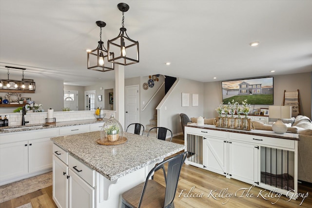 560 Pioneer Trl, Cedar Springs, MI 49319 - kitchen featuring light wood finished floors, a sink, white cabinetry, a kitchen breakfast bar, and open floor plan