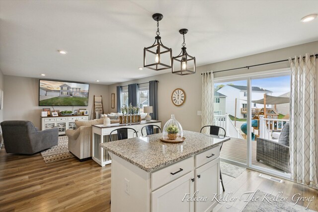 560 Pioneer Trl, Cedar Springs, MI 49319 - kitchen featuring light wood finished floors, white cabinets, a center island, and decorative light fixtures