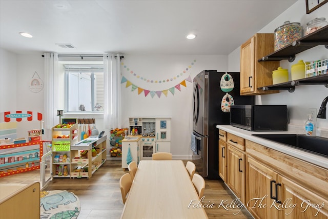 560 Pioneer Trl, Cedar Springs, MI 49319 - kitchen with light wood-style flooring, a sink, open shelves, stainless steel microwave, and light countertops