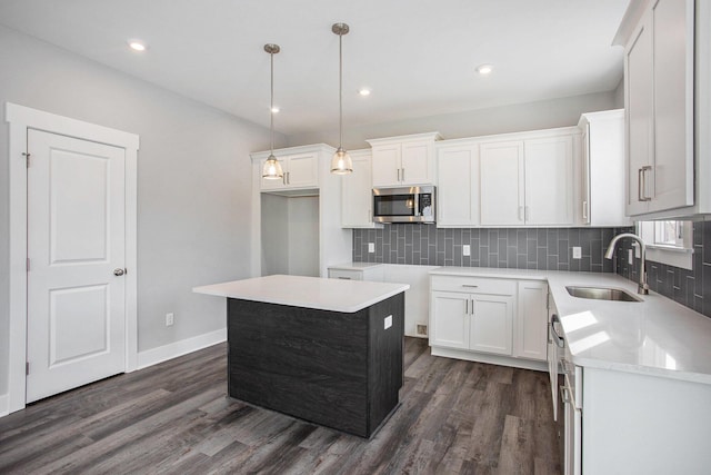 8851 Loggers Ridge Ct SE, Caledonia, MI 49316 - kitchen featuring dark wood finished floors, a sink, stainless steel microwave, white cabinetry, and tasteful backsplash