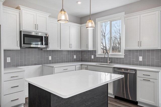 8851 Loggers Ridge Ct SE, Caledonia, MI 49316 - kitchen featuring stainless steel appliances, white cabinets, a sink, and decorative light fixtures