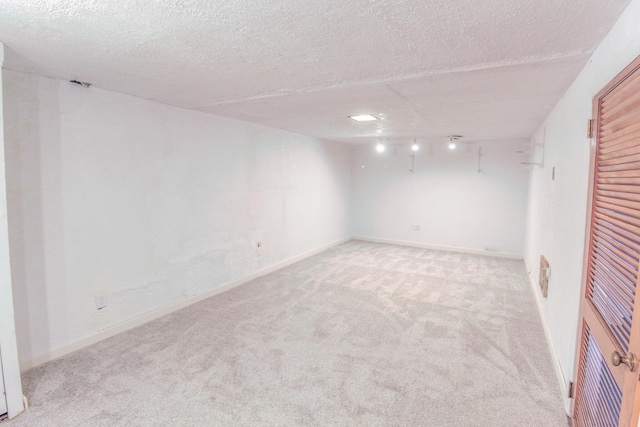 finished basement featuring a textured ceiling, carpet, and baseboards