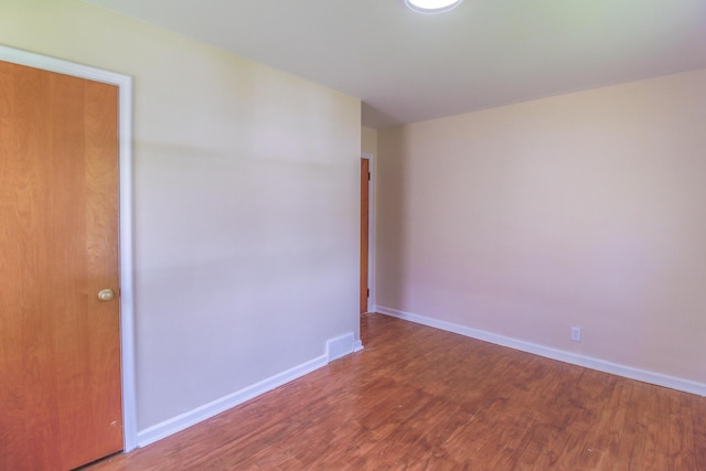unfurnished room featuring visible vents, wood finished floors, and baseboards
