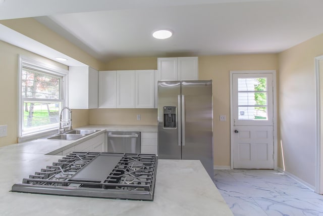 kitchen featuring a sink, stainless steel appliances, white cabinetry, light countertops, and marble finish floor
