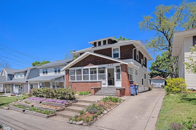 view of front of home featuring brick siding, driveway, a vegetable garden, entry steps, and a detached garage