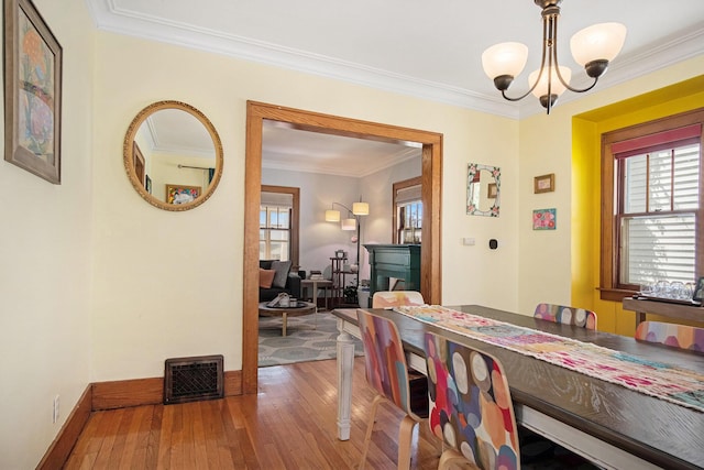 dining space with a chandelier, wood-type flooring, baseboards, and ornamental molding