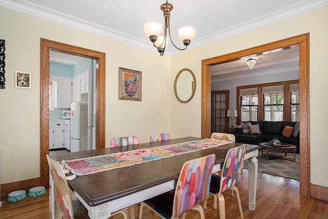 dining room with ornamental molding, wood finished floors, a chandelier, and baseboards