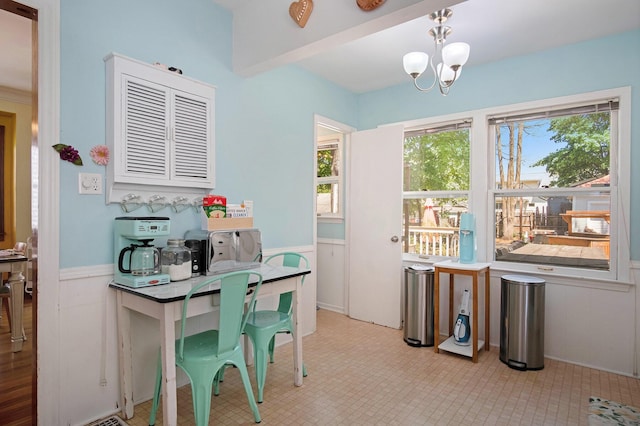 dining space featuring plenty of natural light, wainscoting, and a chandelier