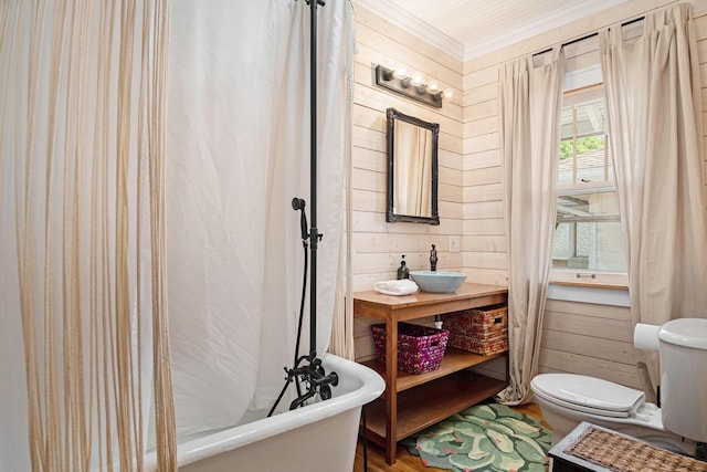 full bath featuring a freestanding tub, toilet, wooden walls, wood finished floors, and vanity
