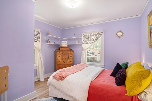 bedroom with crown molding, wood finished floors, and baseboards