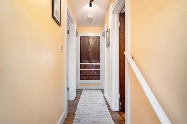 hall with dark wood-type flooring and baseboards