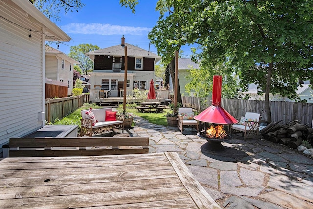 view of patio with a wooden deck, a fenced backyard, and an outdoor living space with a fire pit