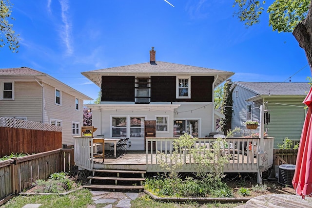 back of house featuring a fenced backyard, a deck, a chimney, and cooling unit