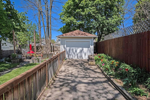 detached garage featuring driveway and fence