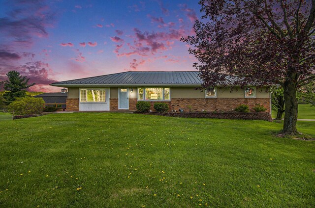 single story home featuring brick siding, a front lawn, and metal roof
